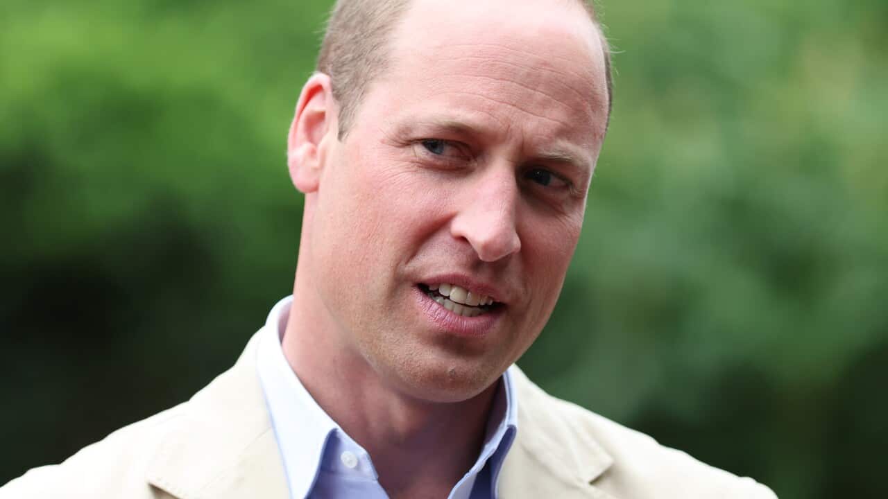 A close up of a man wearing a shirt and blazer who is speaking while standing outside.