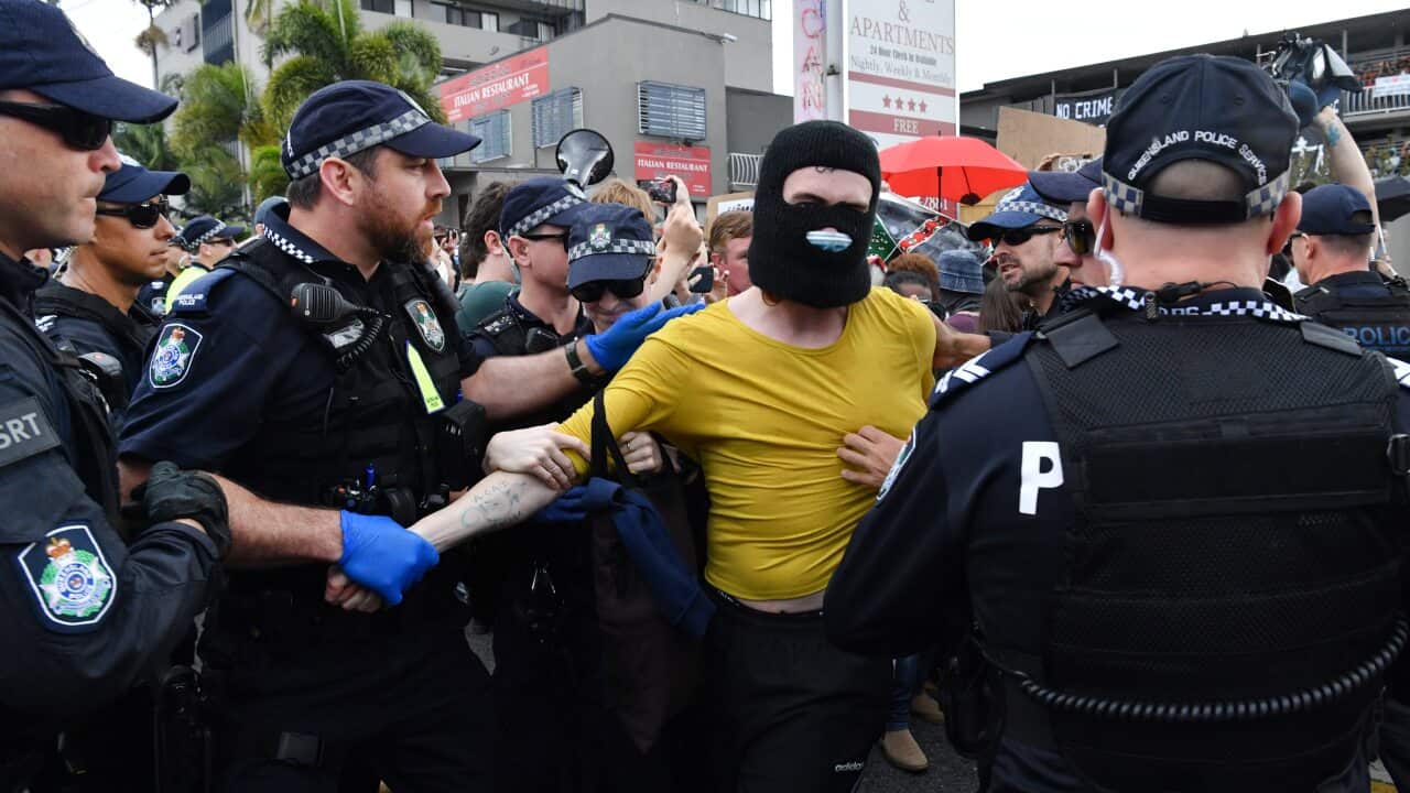 A protester (centre) is seen being detained by police during a rally in support of asylum seekers detained at the Kangaroo Point Central Hotel in Brisbane