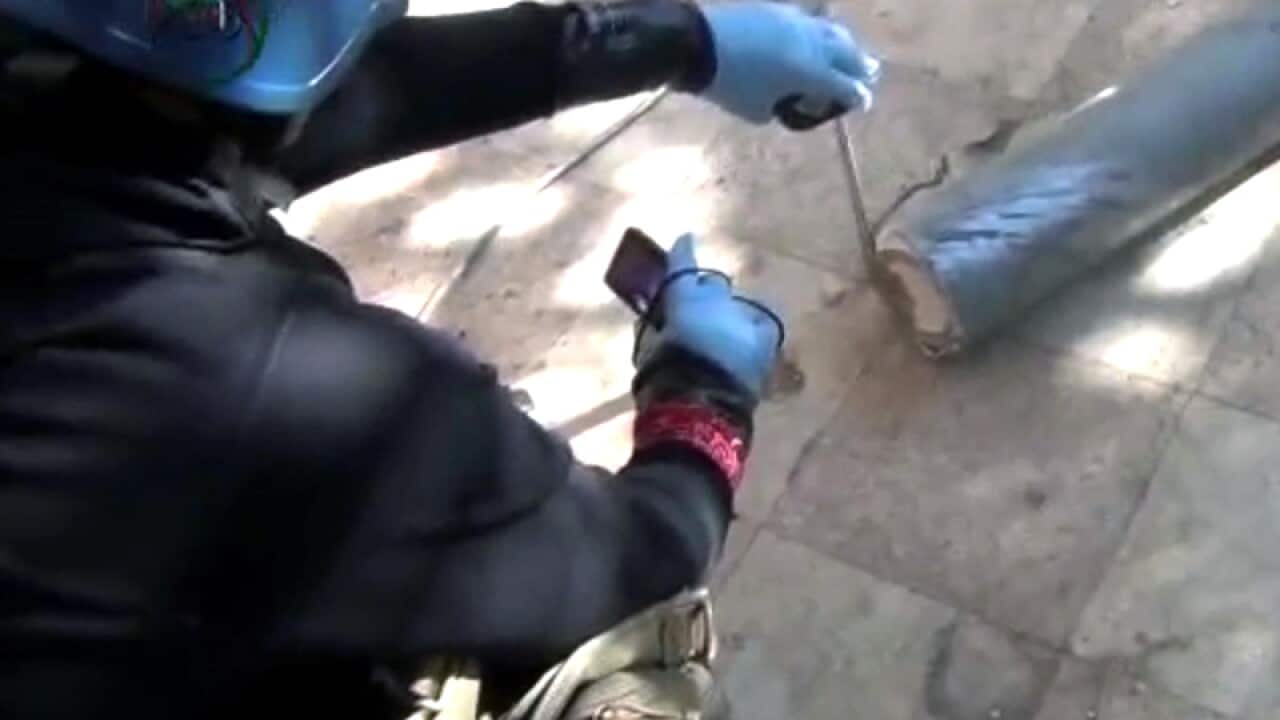 A presumed UN staff member measuring and a canister in Damascus