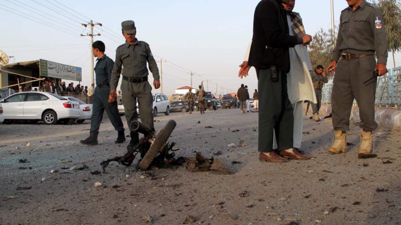 Afghan security officials inspect the site of a bomb blast