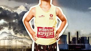 A boy sponsored by Woodside in a yellow singlet stands in front of a skyline with burning fossil fuels