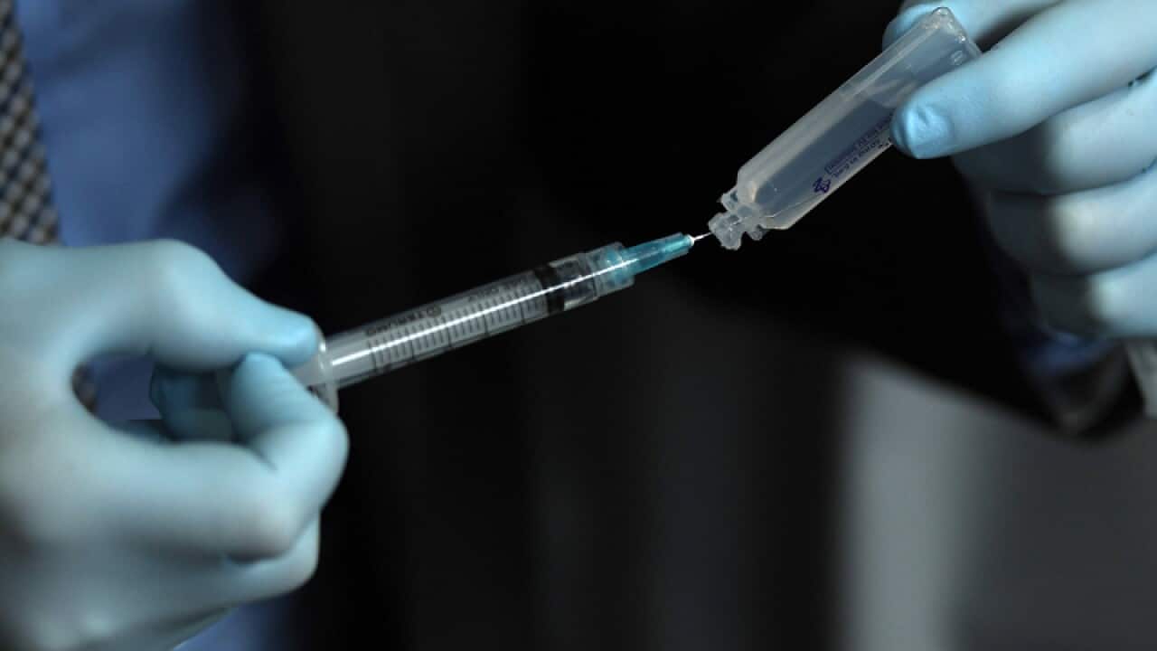 A medical doctor holds a syringe