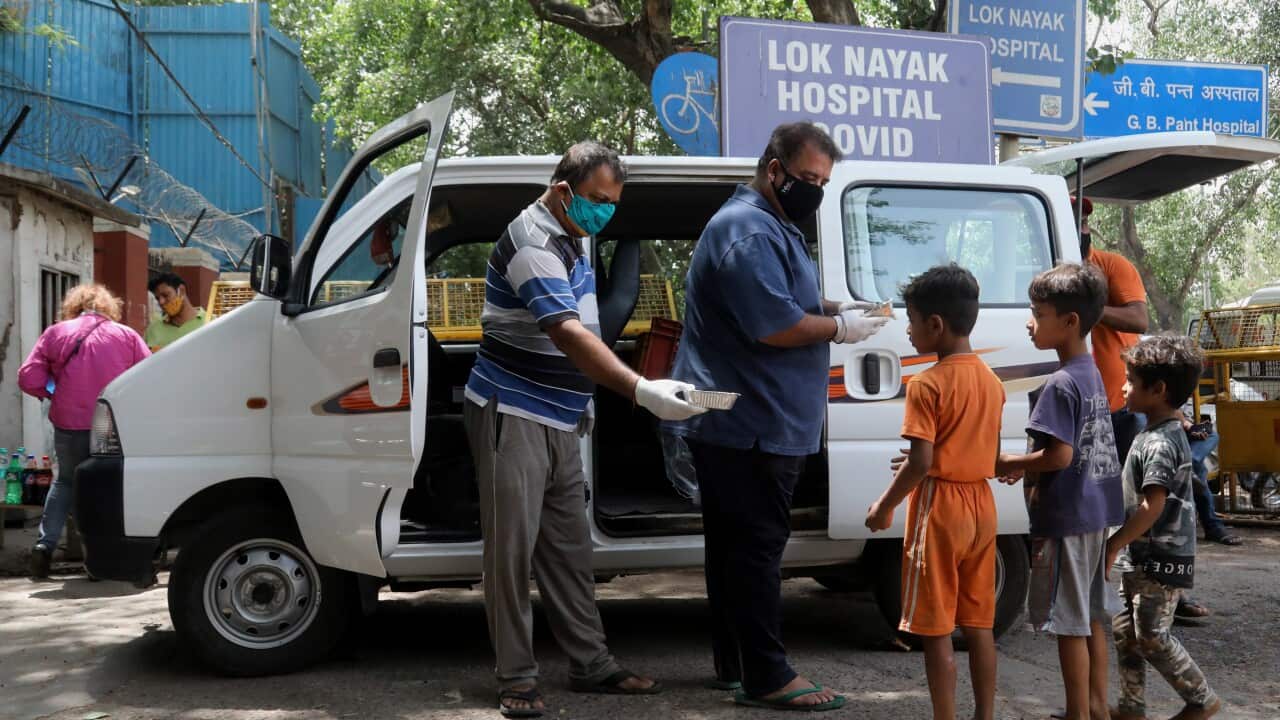 People distribute food to the children outside the care centre.