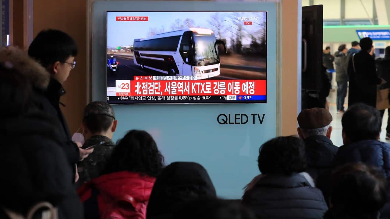 People watch TV coverage of buses carrying a North Korean advance team to South Korea at Seoul Station.