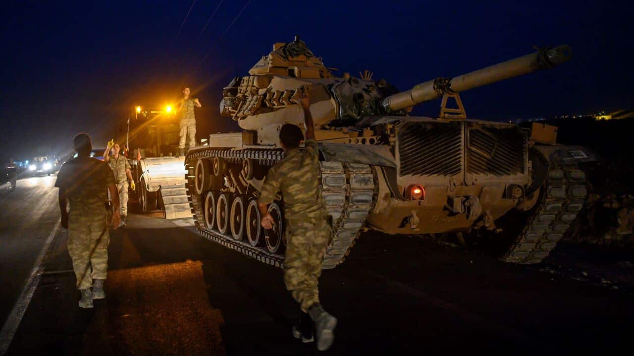 A Turkish army's tank drives down from a truck as Turkish armed forces drive towards the border with Syria.