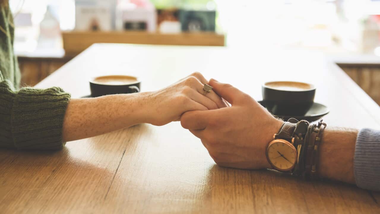 Close up of Caucasian couple holding hands in coffee shop