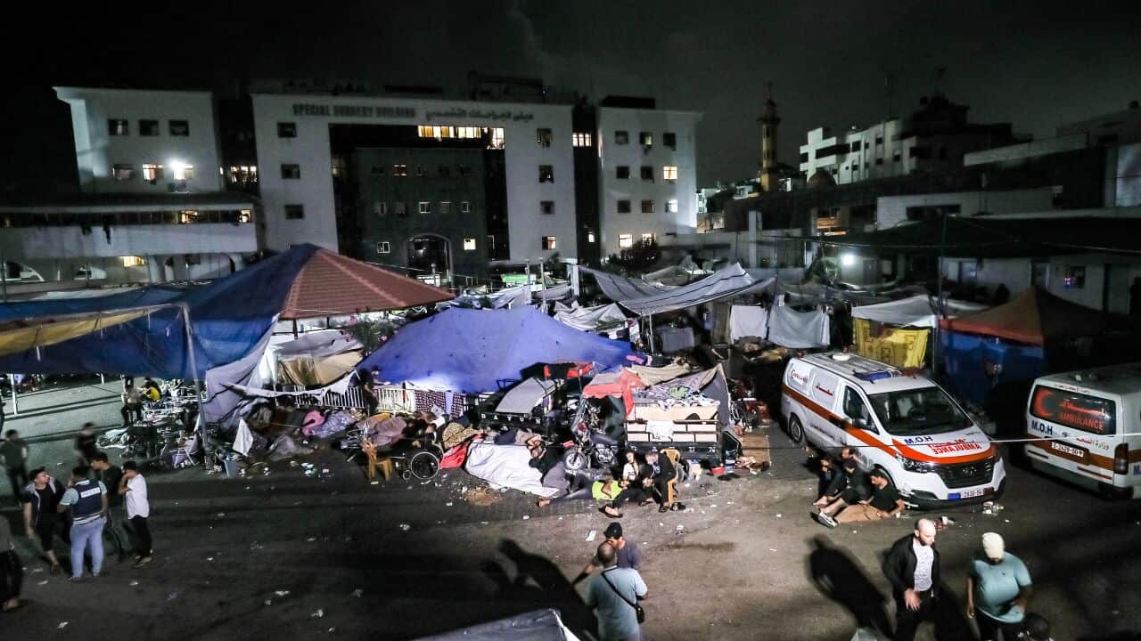 A group of people stand outside a hospital.