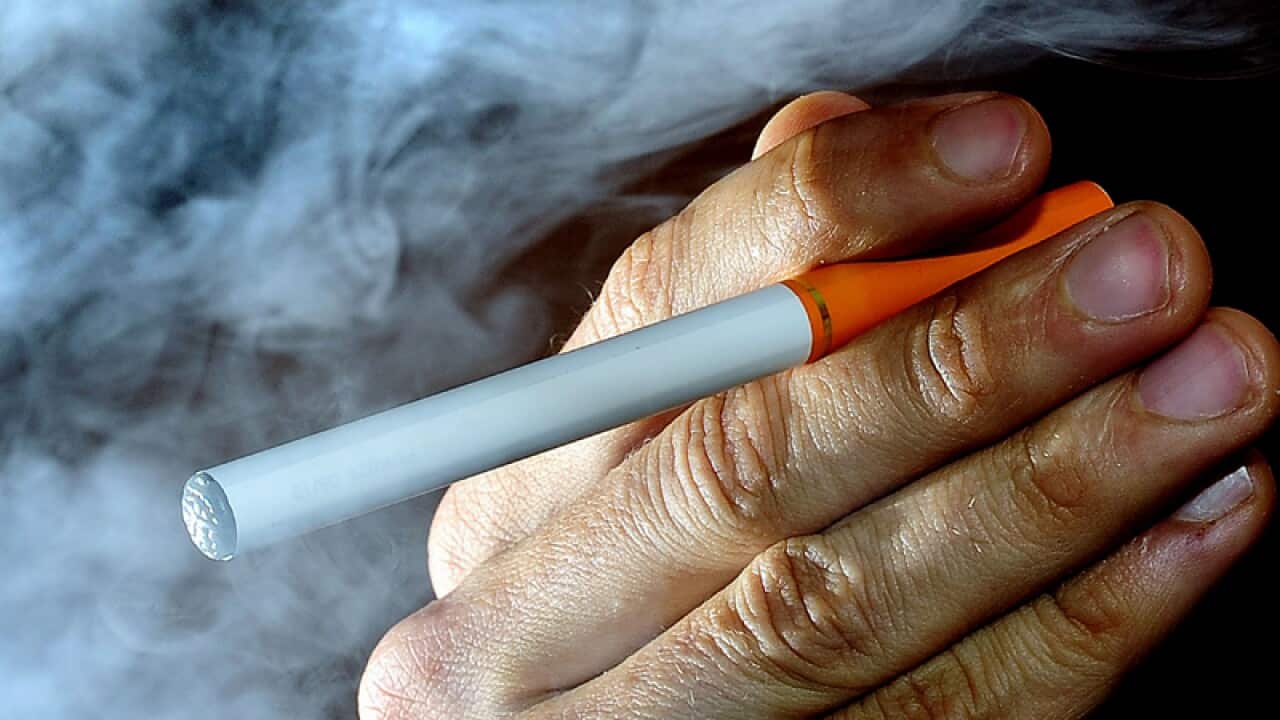 A person poses with an electronic cigarette.
