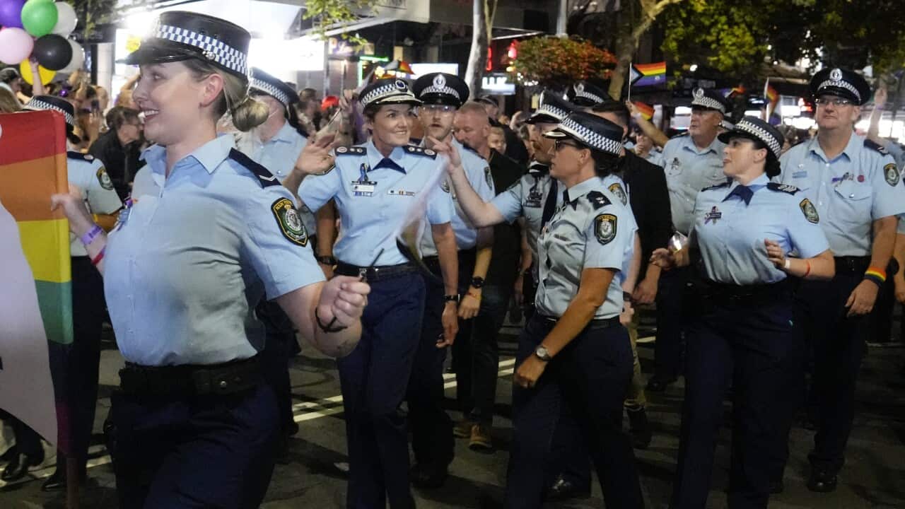 A group of police officers in uniform marching at Mardi Gras.