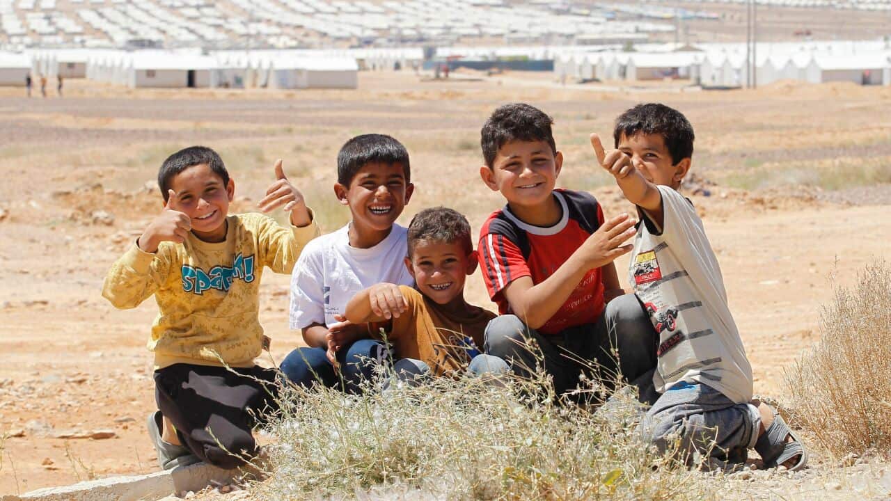 Syrian refugee boys gesture to the camera during the inauguration ceremony of a new solar power plant at the Azraq camp for Syrian refugees in northern Jordan on May 17, 2017.