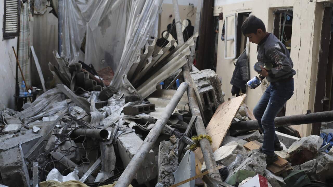 A Palestinian boy salvages canned food after an Israeli strike on residential buildings in Rafah, Gaza Strip (AAP)