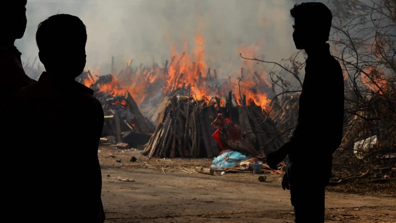 Family members look on as COVID-19 victims are cremated in New Delhi