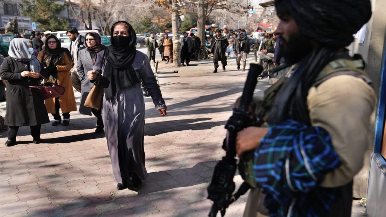 Afghan women pass next of Taliban fighter in Kabul, Afghanistan, Sunday, 13 February, 2022.