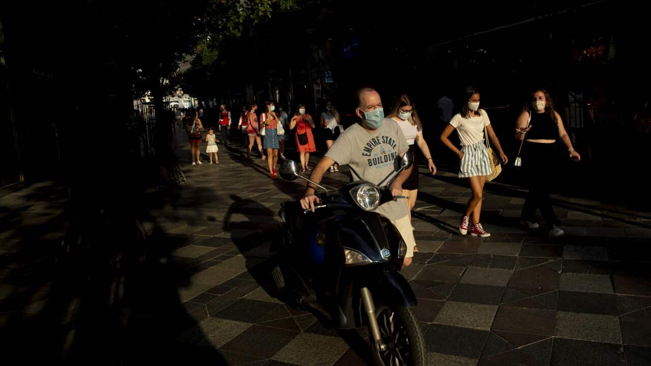 People wearing face masks to prevent the spread of coronavirus, walk along a street in downtown Madrid, Spain.