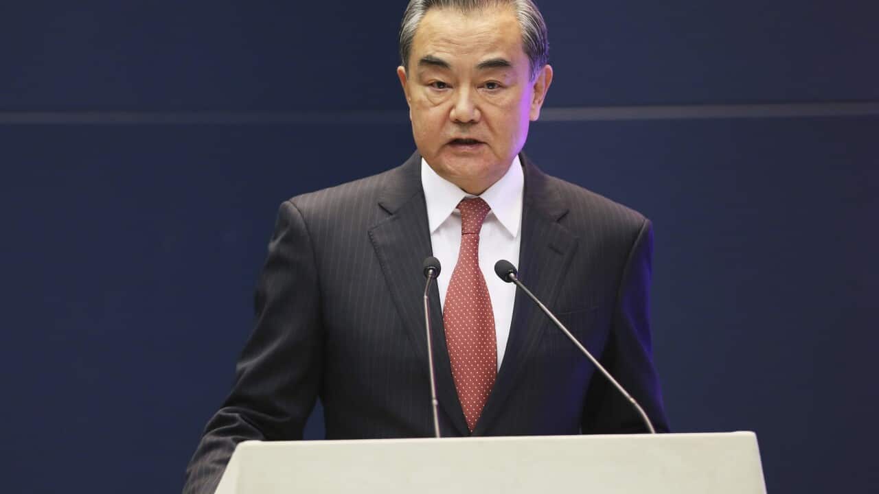 China's Foreign Minister, Wang Yi, stands at a podium.