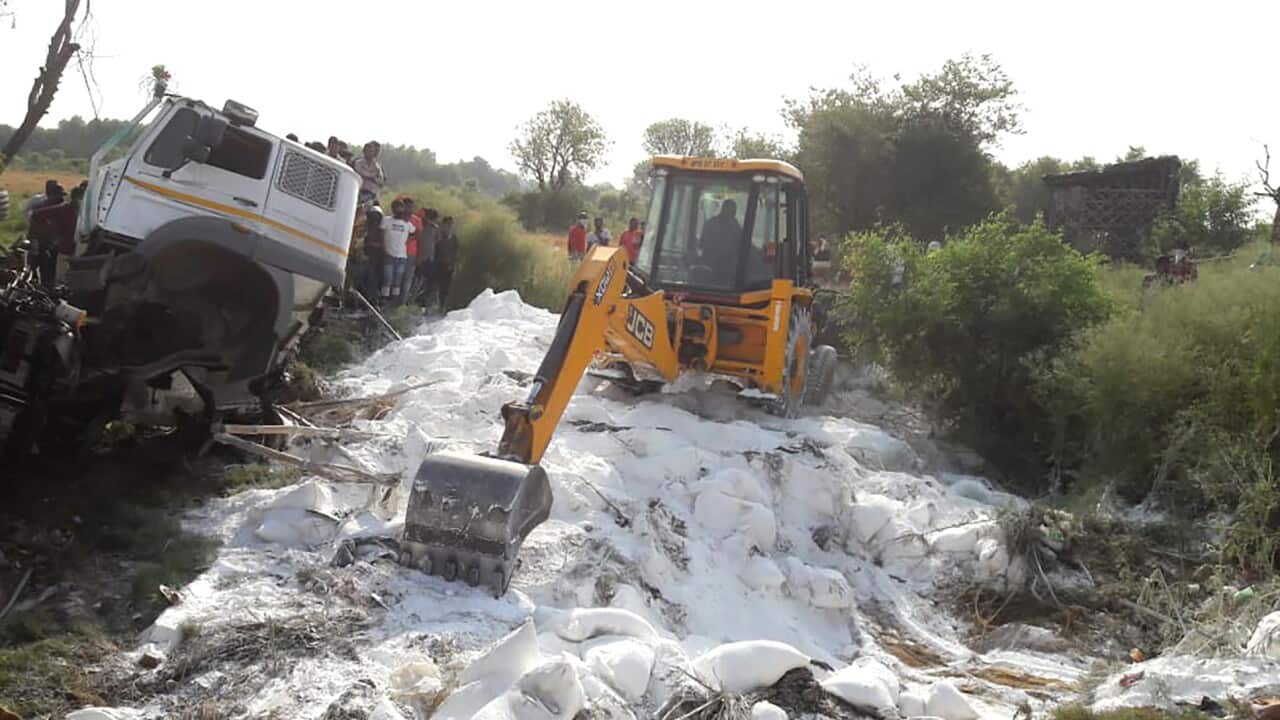 An excavator clears bags of cement scattered on a road after a truck accident near Auraiya, a village in Uttar Pradesh state, India, Saturday, May 16, 2020.