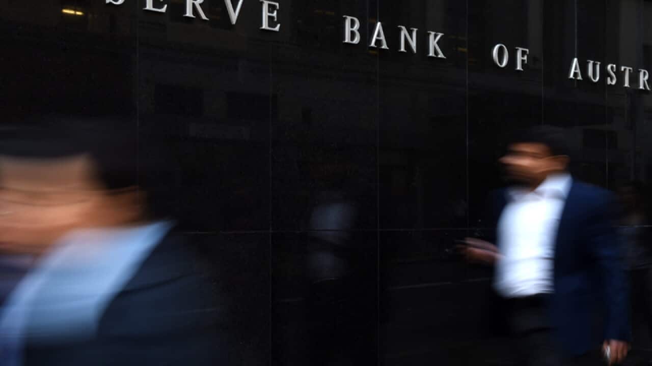 Pedestrians walk past the Reserve Bank of Australia