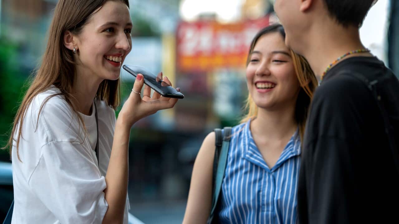 Three people communicate through a device with AI-powered translation capabilities.