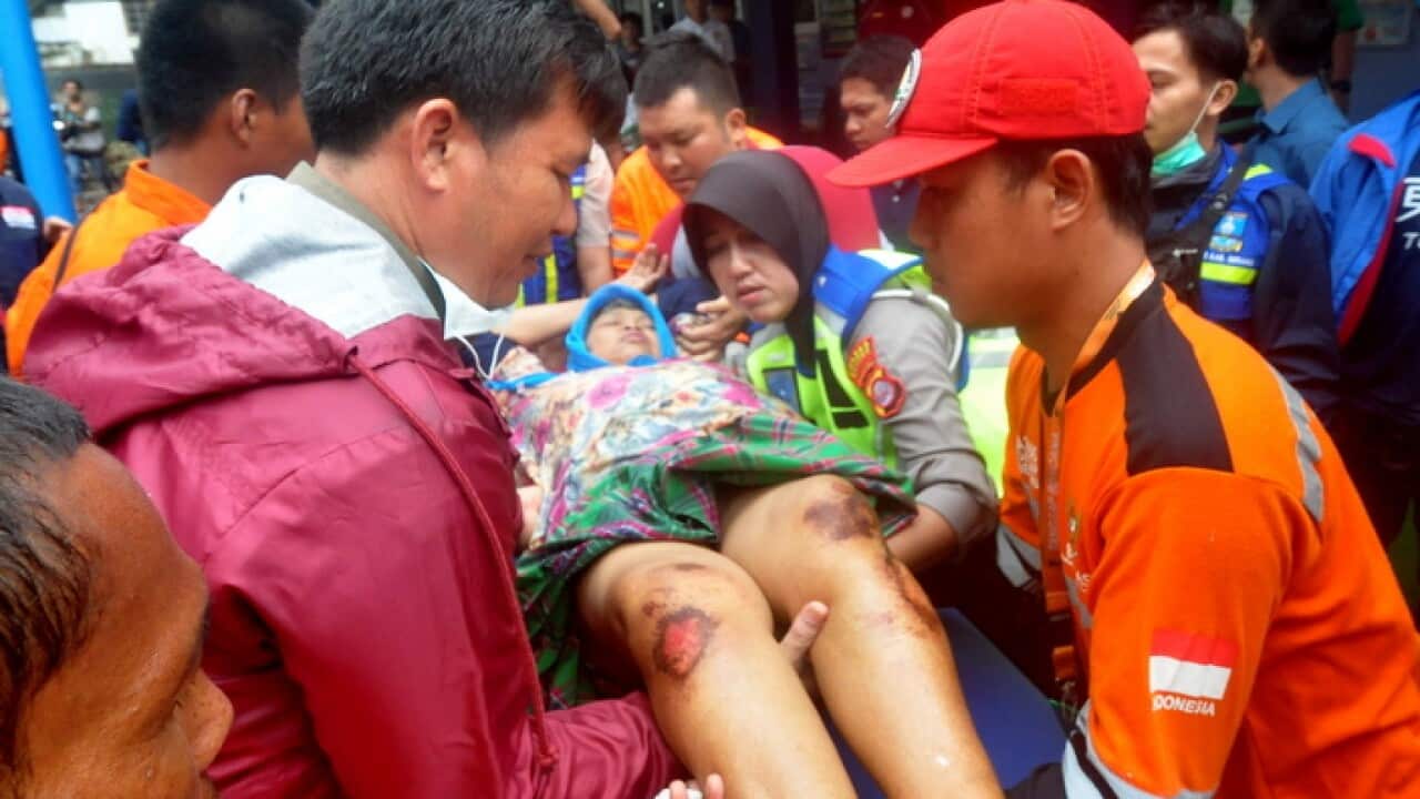 Emergency services personnel carry an injured person into an ambulance after a tsunami hit the Sunda Strait off Indonesia