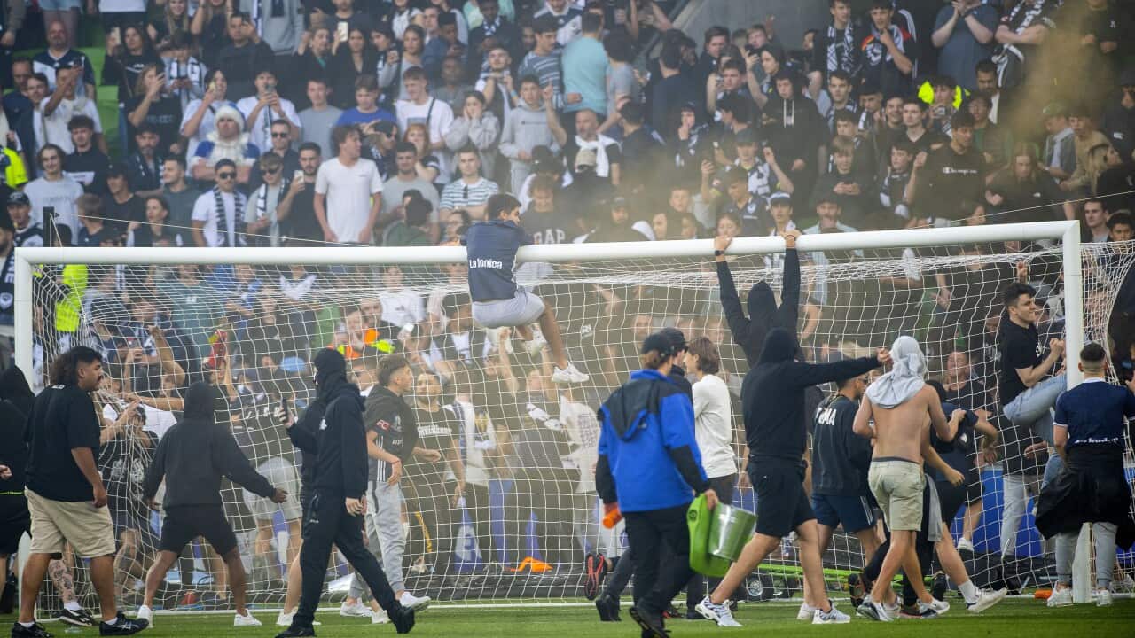 Fans invade a pitch during a football match in Melbourne.
