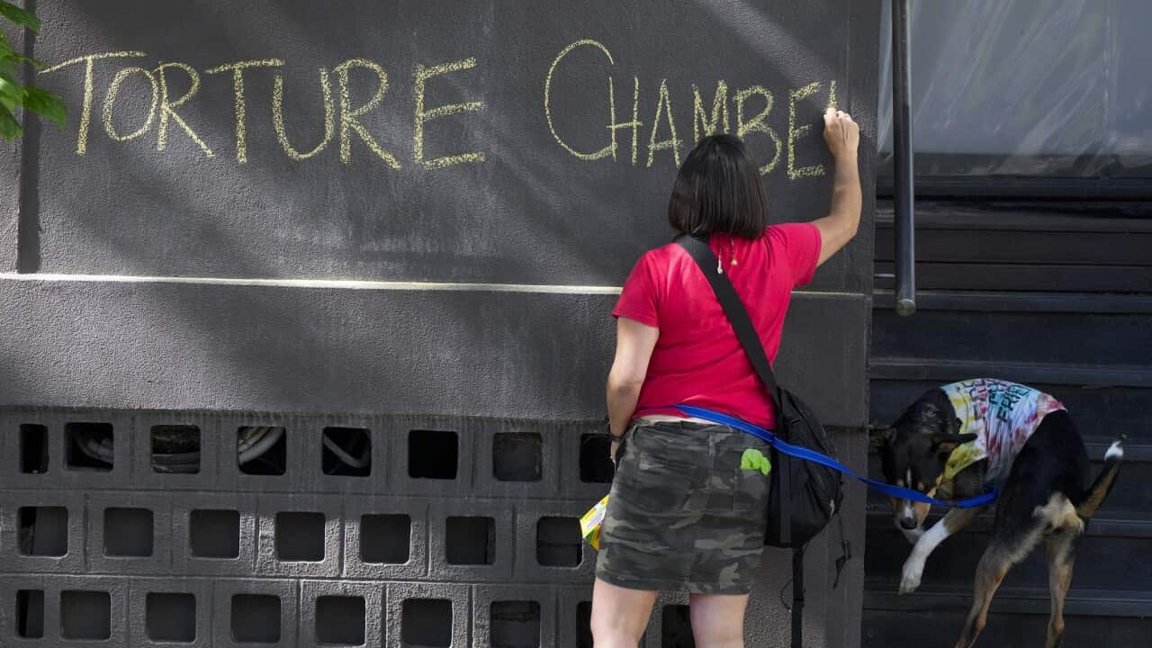 A refugee advocate writes a slogan on the wall outside the Park Hotel, used as an immigration detention hotel (AAP).