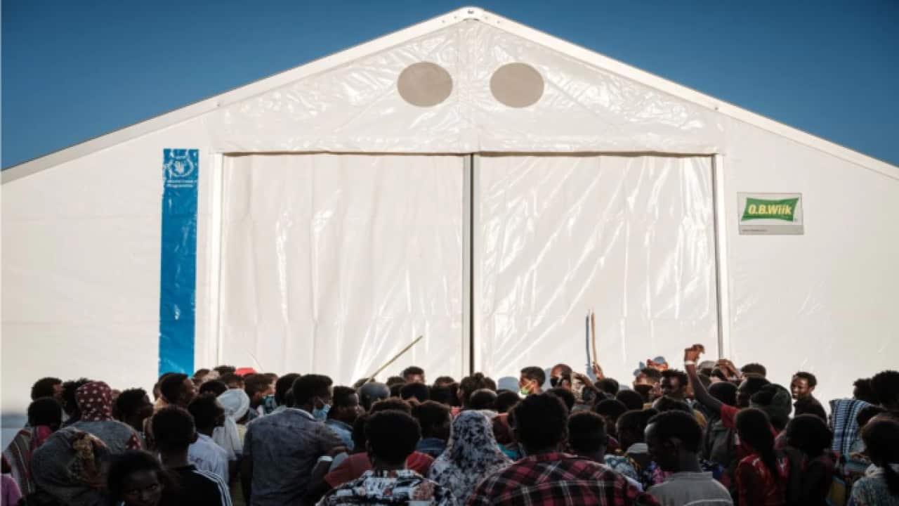 Refugees from Tigray outside a tent waiting for a humanitarian aid