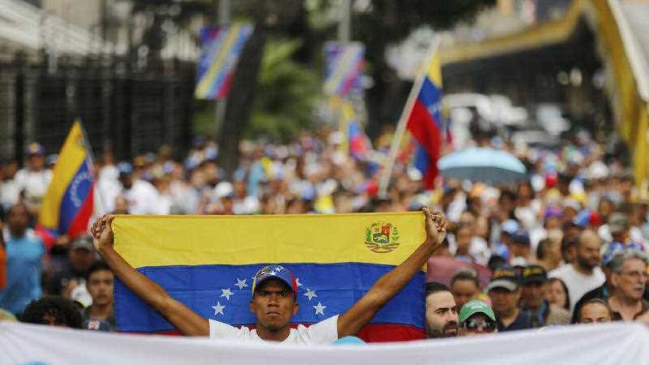 An opposition member holds a Venezuelan national flag during a protest march against President Nicolas Maduro in Caracas, Venezuela.