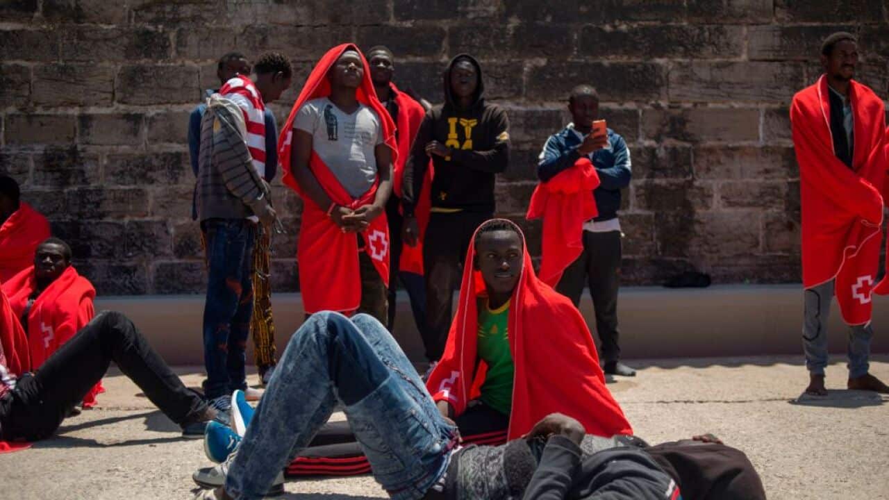 Migrants keep warm wrapped in Red Cross blankets after arriving aboard a coast guard boat at Tarifa's harbour on July 14, 2018.