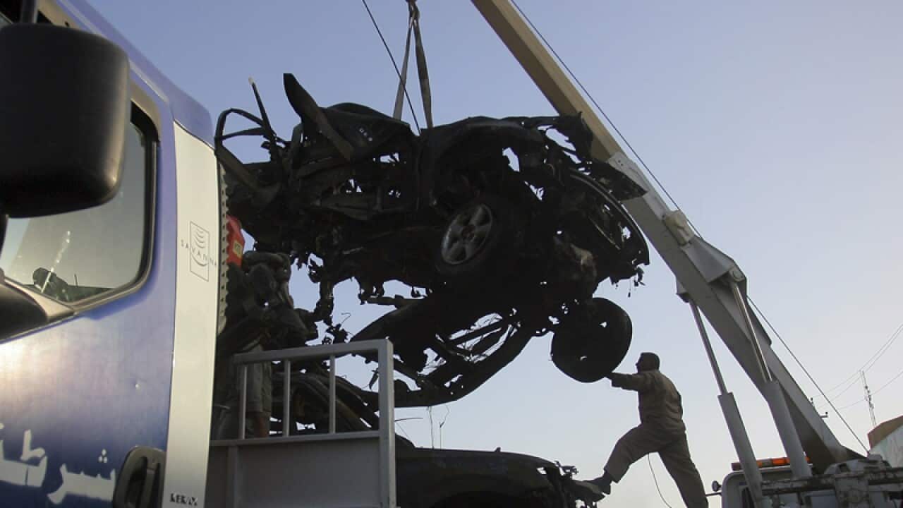 Iraqi security forces remove destroyed vehicles following a bombing