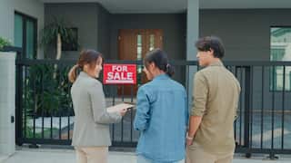Young Asian woman real estate broker showing house to client buyers outside at home. Buying a new house.