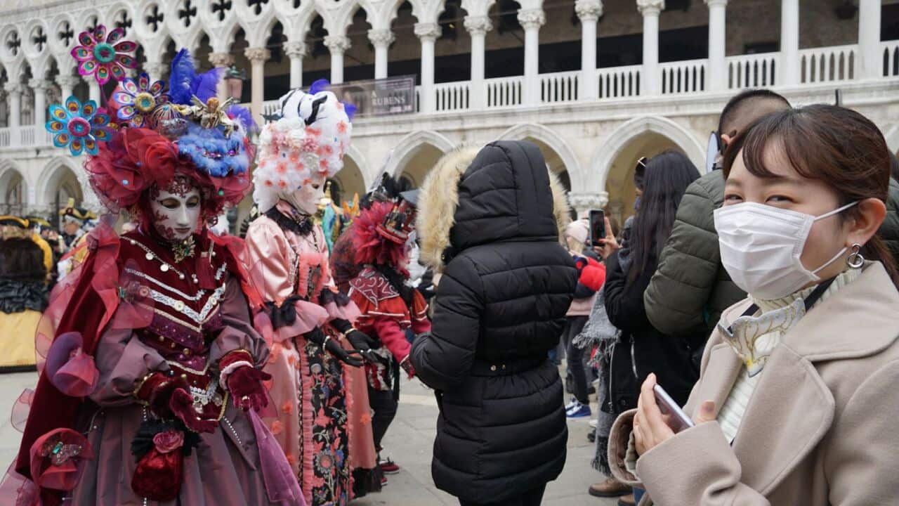 A tourist (R) wearing a protective face mask visits Piazza San Marco, in Venice, Italy, 24 February 2020, during the usual period of the Carnival festivities.