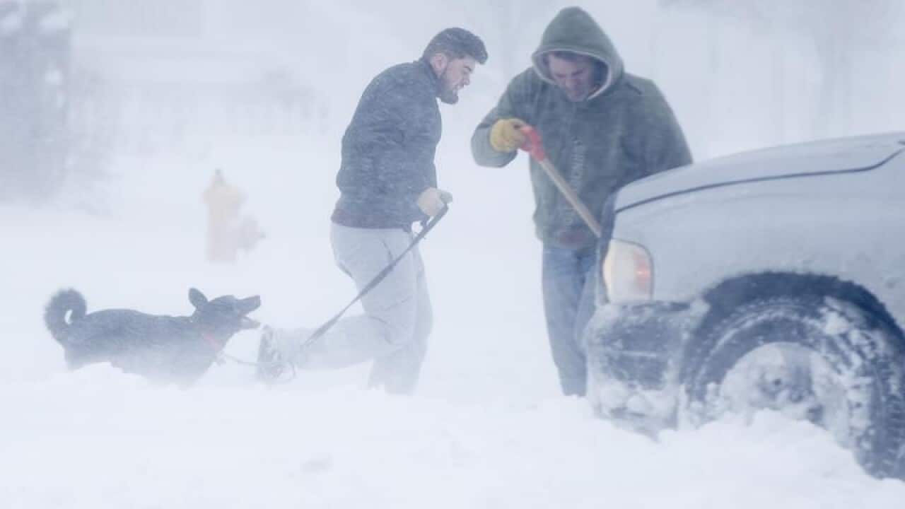 A man walks his dog as another struggles to dig out his truck