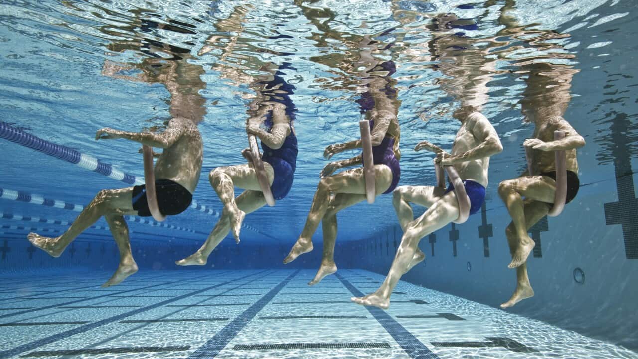 Five senior people in swimming pool, underwater, low section