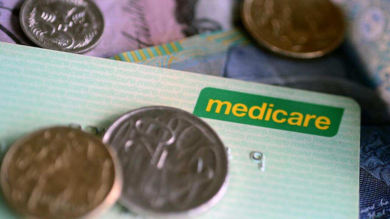 Bank notes and coins are seen with a Medicare Card in Brisbane, Wednesday, May 1, 2013. Prime Minister Julia Gillard today announced a levy to fund the National Disability Insurance Scheme. (AAP Image/Dave Hunt) NO ARCHIVING