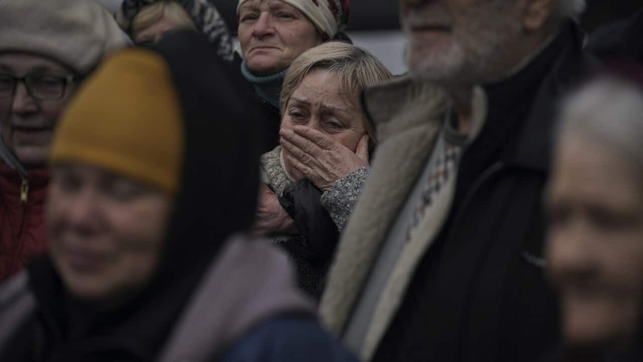 A woman cries as residents listen to a Ukrainian serviceman speaking after a convoy of military and aid vehicles arrived in the formerly Russian-occupied Kyiv suburb of Bucha on 2 April 2022.