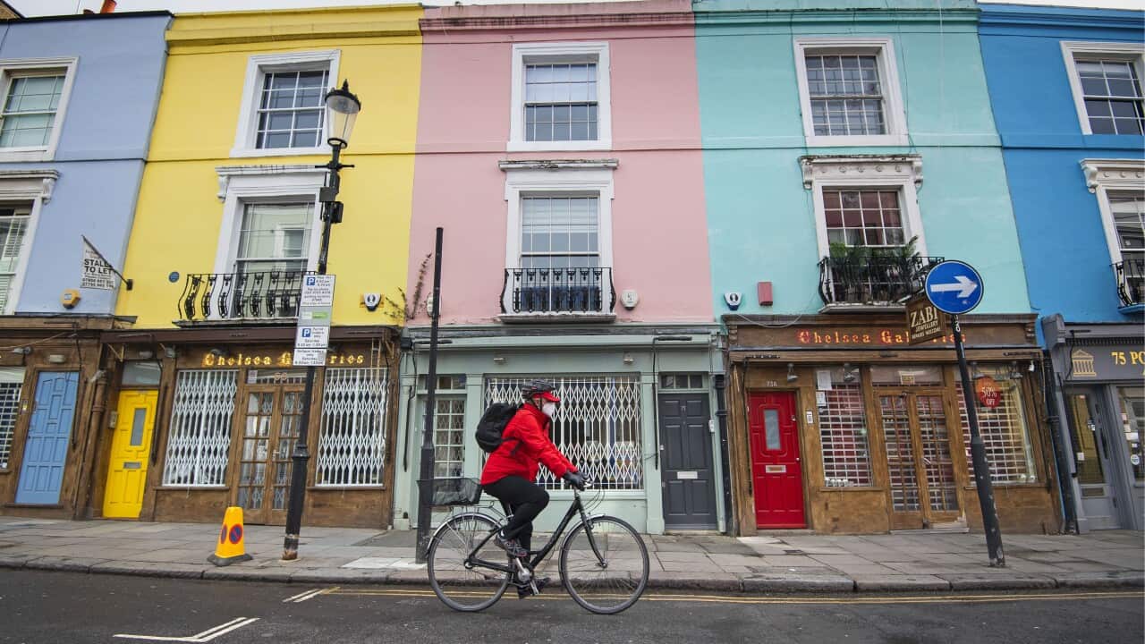 A cyclist wearing a face mask rides past closed up shops on Portobello Road in West London as the UK continues in lockdown.