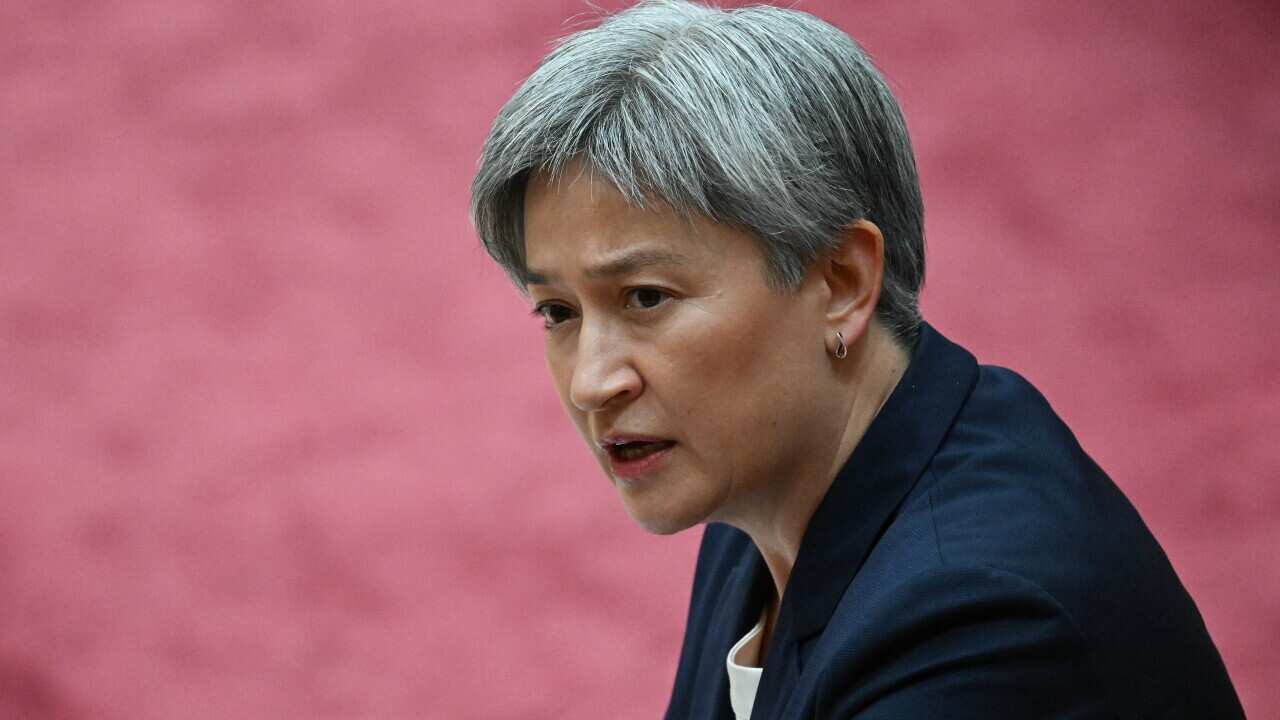 Penny Wong sitting down. A pink floor is visible in the background.