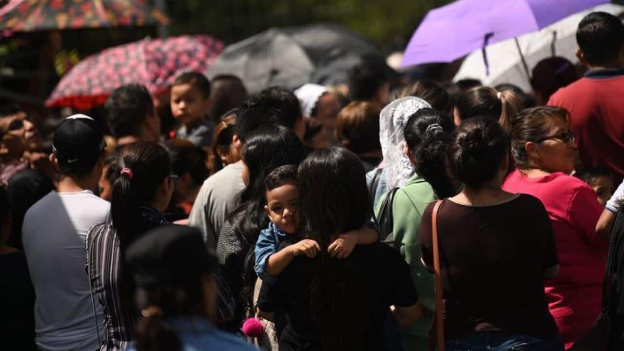 A boy is carried by his mother as they attend the funeral of Salvadoran migrant Oscar Martinez and his almost two-year-old daughter Angie Valeria,