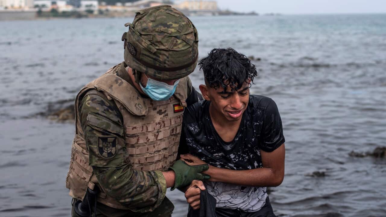 A Spanish soldier helps a migrant at his arrival at El Tarajal beach, in Ceuta, Spain on 19 May 2021.
