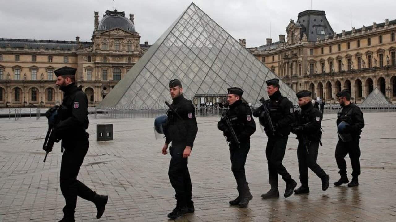 Armed police officers patrol in the courtyard of the Louvre museum near where a soldier opened fire after he was attacked in Paris
