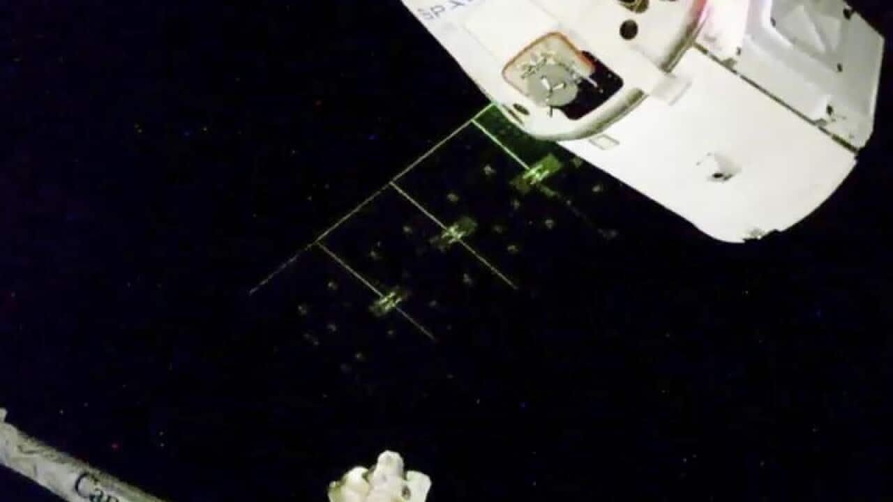A spacecraft approaches the International Space Station's docking arm