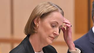 Telstra CEO Vicki Brady, a woman in her 50s with short blonde hair and dressed in a dark blazer puts a hand to her forehead.