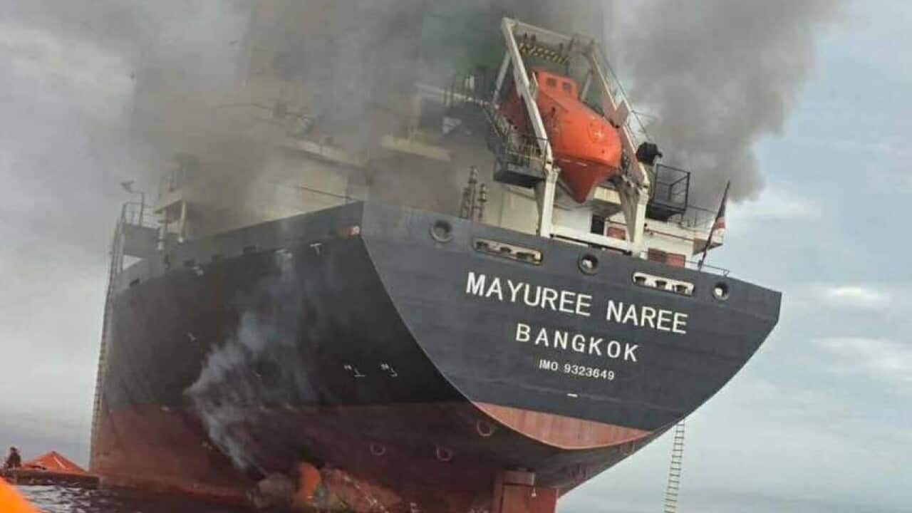 A large ship in the water, with smoke rising from it.