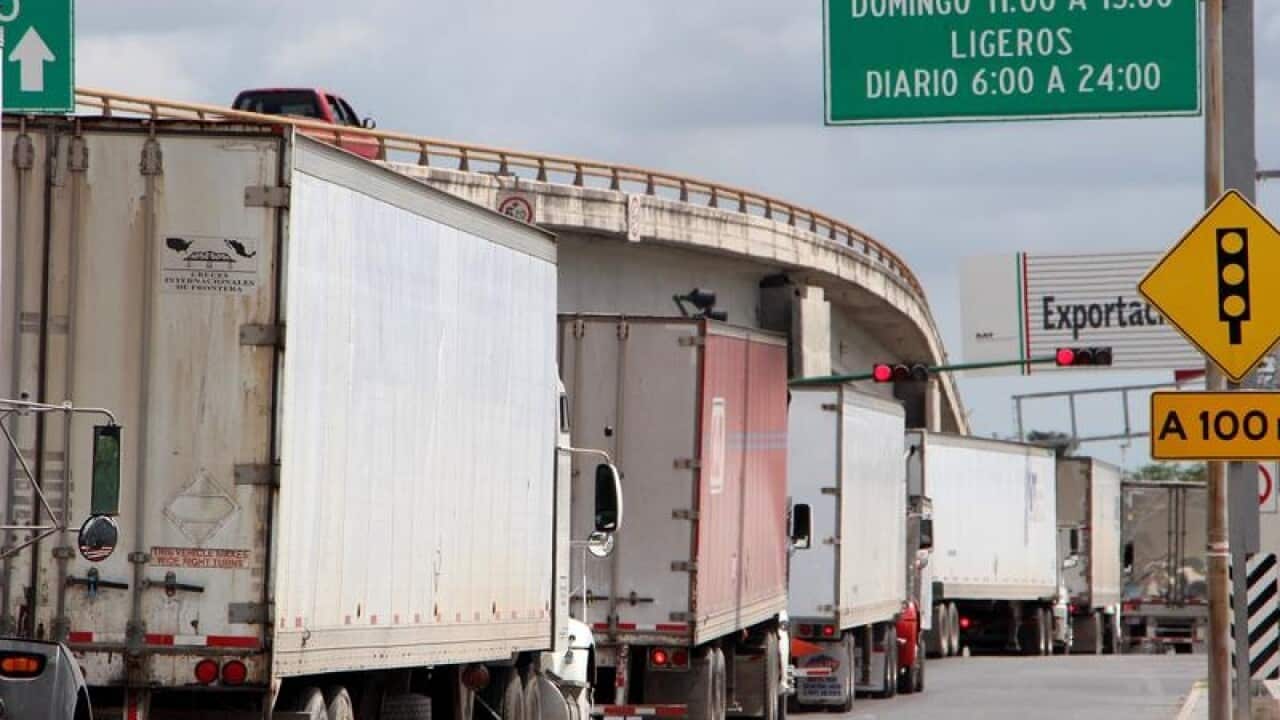 Mexican trucks wait to carry goods into the US