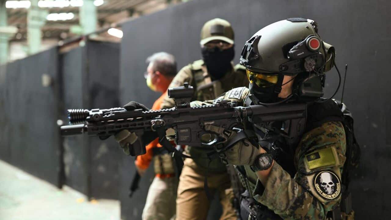 Trainees prepare to enter a building with their airsoft guns during an airsoft gun shooting lesson