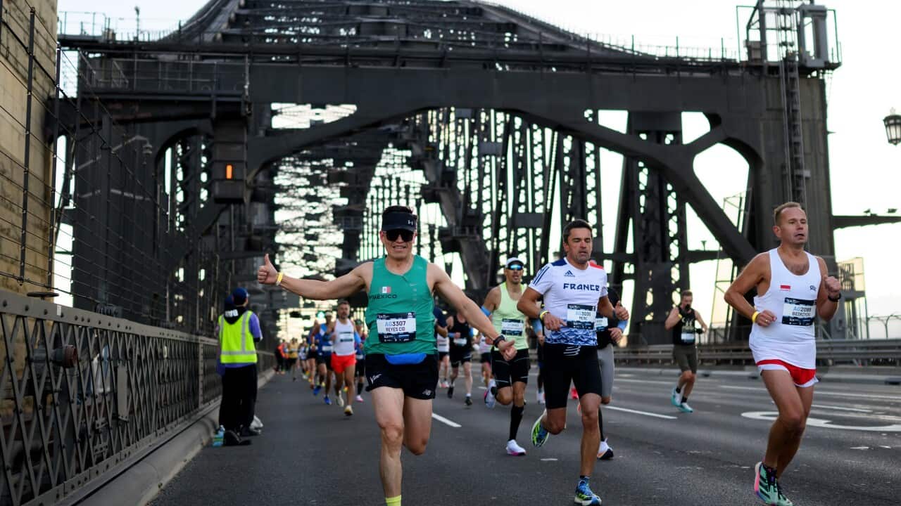 People run on a bridge as part of a marathon running event.