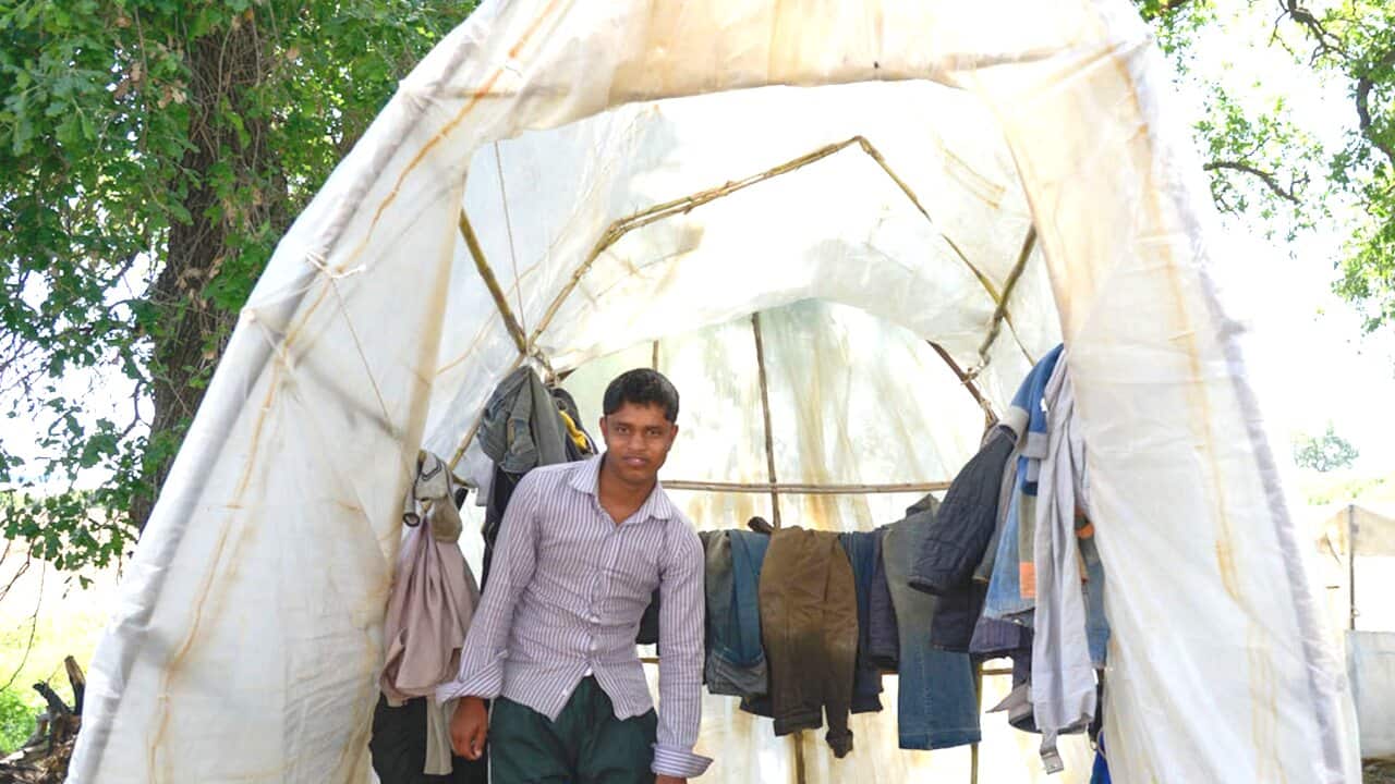 A foreign worker stands in a tent-like settlement at a strawberry cultivation in Malolada, southern Greece