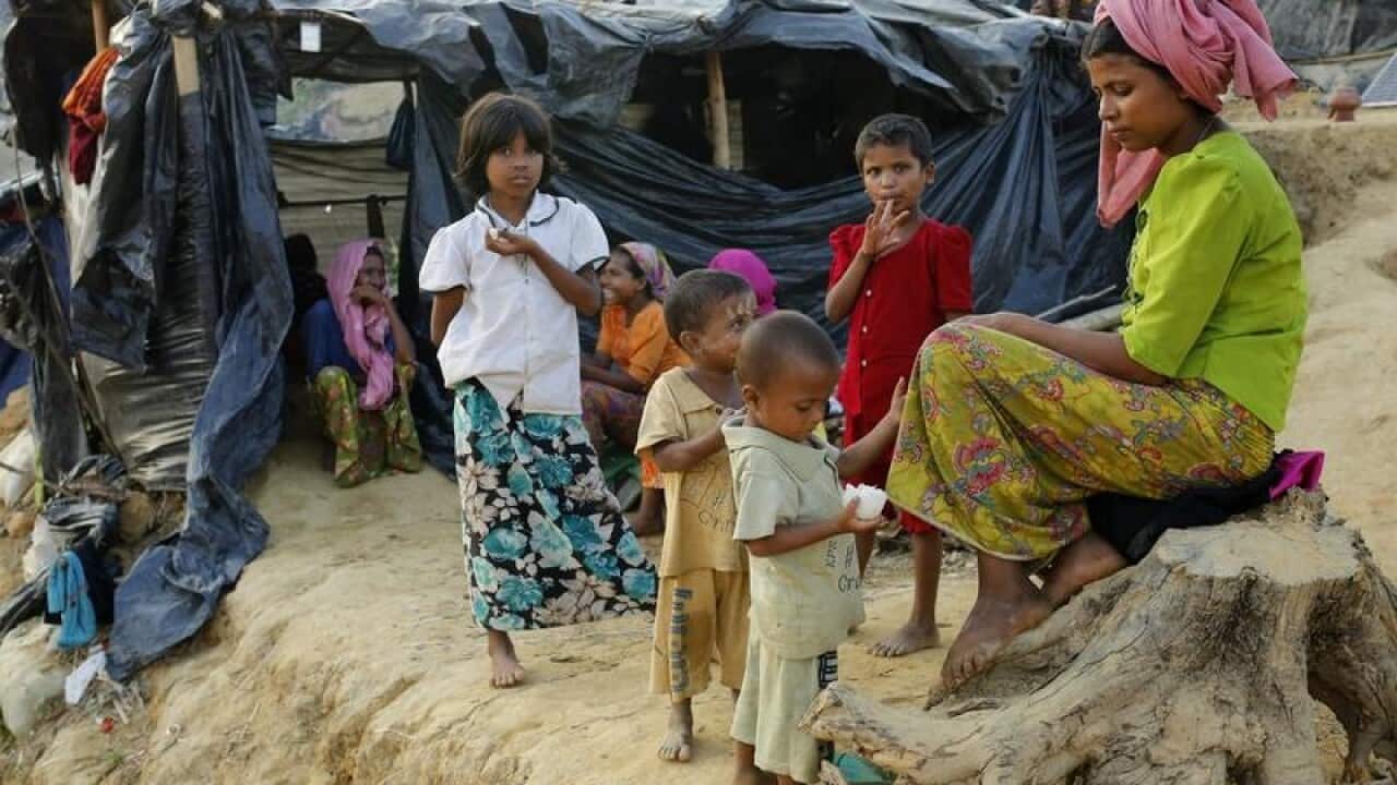 Family members of Rohingya refugees sit in front tents at Balukhali.