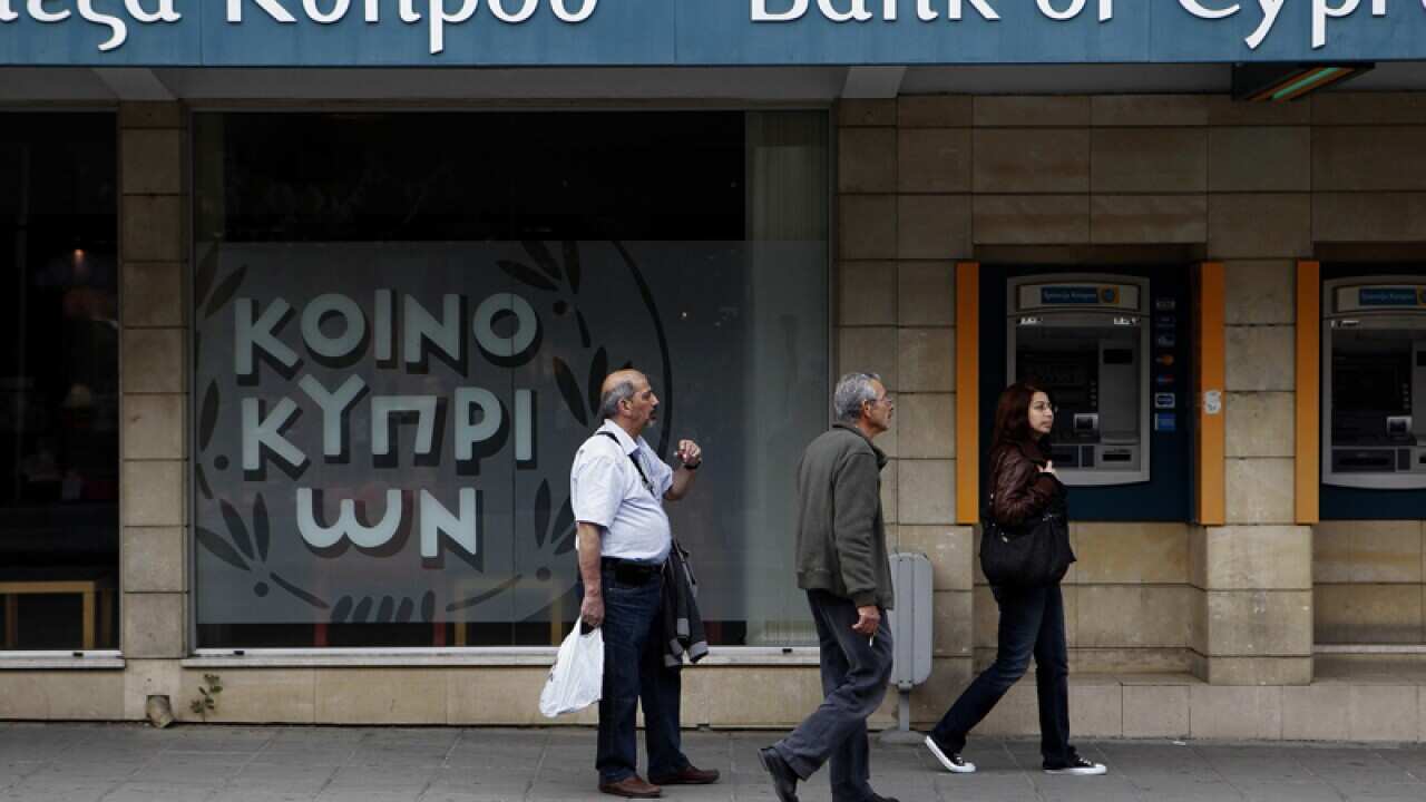 People pass a branch of the Bank of Cyprus