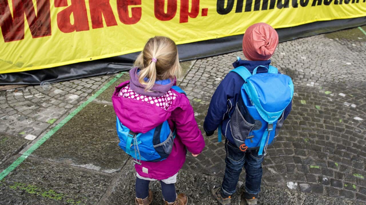 Two Children stay in front of a banner